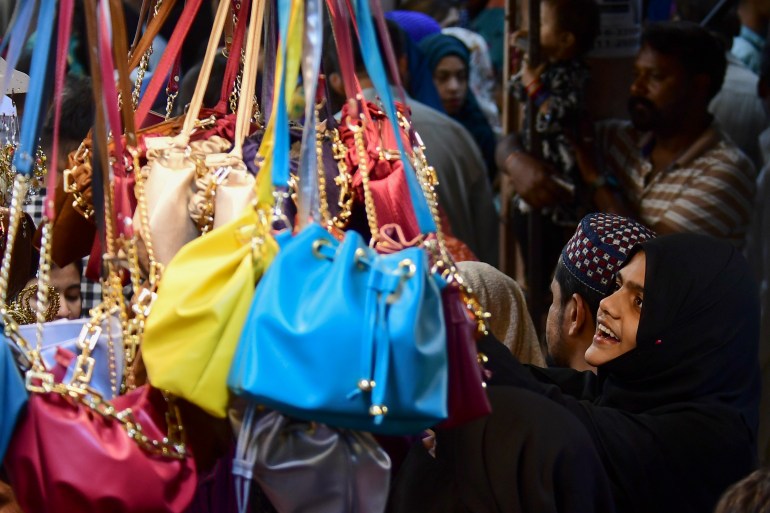 A girl looks at handbags during shopping at a market ahead of the upcoming festival of Eid al-Fitr in Karachi on April 19, 2023. (Photo by Asif HASSAN / AFP)