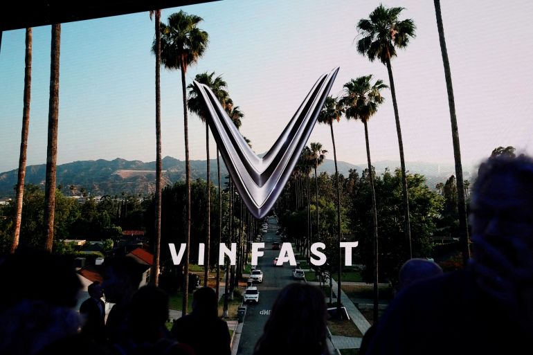 FILE PHOTO: People walk next to a VinFast logo on a screen during the press day at the Los Angeles Auto Show in Los Angeles, California, U.S. November 17, 2022. REUTERS/Mike Blake/File Photo/File Photo/File Photo
