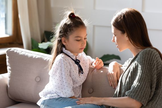 Upset small schoolgirl having trustful conversation with compassionate young mother, sitting together on sofa. Wise mommy comforting soothing little child daughter, overcoming problems at home.; Shutterstock ID 1686988003; purchase_order:multimedia; job:; client:; other: