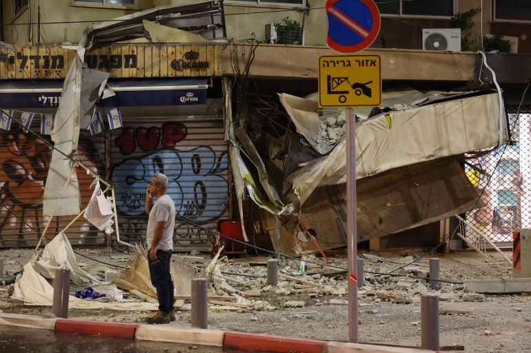 A man stands in front of a damaged shop in Tel Aviv, after it was hit by a rocket fired by Palestinian militants from the Gaza Strip on October 7, 2023. - Palestinian militant group Hamas launched a surprise large-scale attack against Israel on October 7, firing thousands of rockets from Gaza and sending fighters to kill or abduct people as Israel retaliated with devastating air strikes. (Photo by JACK GUEZ / AFP)