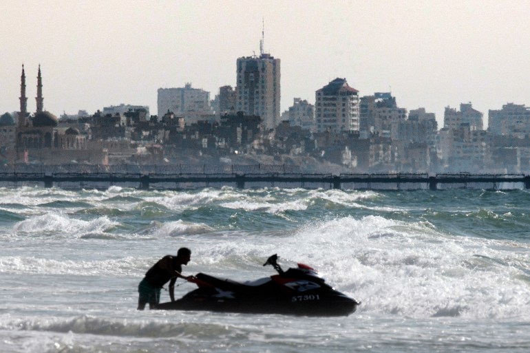 An Israeli man pushes a jetski off a in the southern Israeli Kibbutz of Zikim, the closest Israeli beach to the Gaza Strip (background), on September 12, 2014. Israel and the Islamist movement Hamas that dominates Gaza agreed a truce on August 26, 2014 to end a 50-day war that killed more than 2,200 people and caused enormous destruction in the besieged coastal territory. AFP PHOTO/ JACK GUEZ (Photo by JACK GUEZ / AFP)