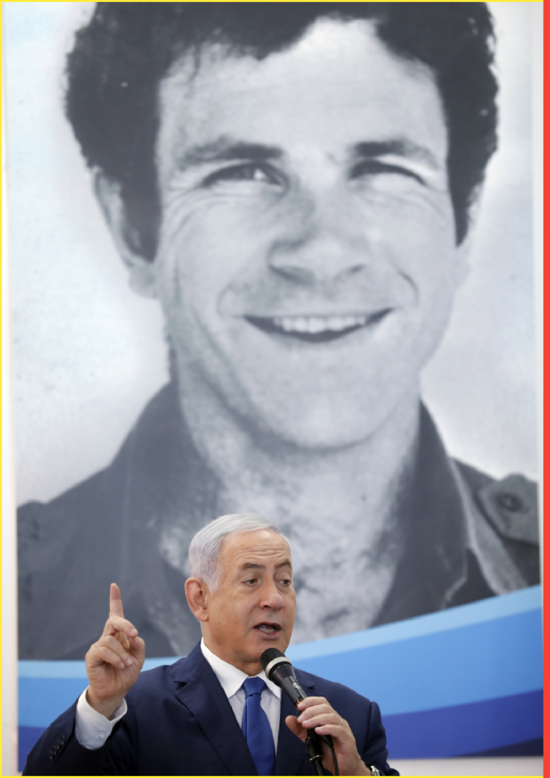 Israeli Prime Minister Benjamin Netanyahu speaks to students as he stands in front of a banner depicting his late brother Yonatan "Yoni" Netanyahu, during a dedication ceremony at Ort Samaria Ulpana school in the Jewish settlement of Elkana in the Israeli-occupied West Bank on Sunday, September 1, 2019.
