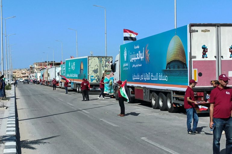 Egyptian volunteers wait next to a convoy of trucks carrying humanitarian aid to Palestinians by Egyptian NGOs, as they wait for an agreement on the Rafah border crossing to enter Gaza, amid the ongoing conflict between Israel and the Palestinian Islamist group Hamas, in the city of Al-Arish in Egypt's Sinai peninsula, Egypt, October 15, 2023. REUTERS/Stringer
