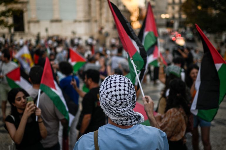 A protestor with a keffieh waves a Palestinian flag during a rally in support of Palestinians at Camoes square in Lisbon on October 9, 2023 after the Palestinian militant group Hamas launched an attack on Israel. - Israel, reeling from the deadliest attack on its territory in half a century, formally declared war on Hamas Sunday as the conflict's death toll surged close to 1,000 after the Palestinian militant group launched a massive surprise assault from Gaza. (Photo by Patricia DE MELO MOREIRA / AFP)