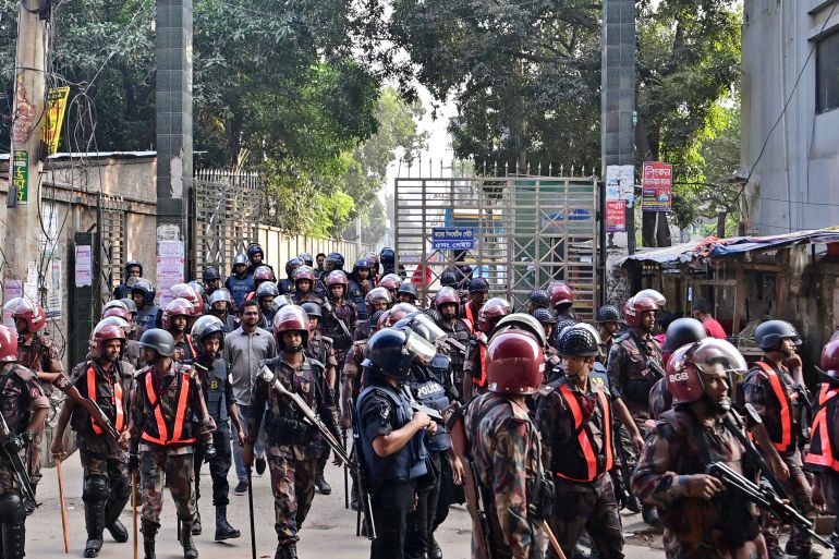 Security personnel stand guard along a street to oversee a protest by garment workers in Gazipur on November 9, 2023. - Up to 25,000 garment workers clashed with police in Bangladesh on November 9, officials said, as protests rejecting a government-offered pay rise forced the closure of at least 100 factories outside Dhaka. (Photo by Munir uz ZAMAN / AFP)