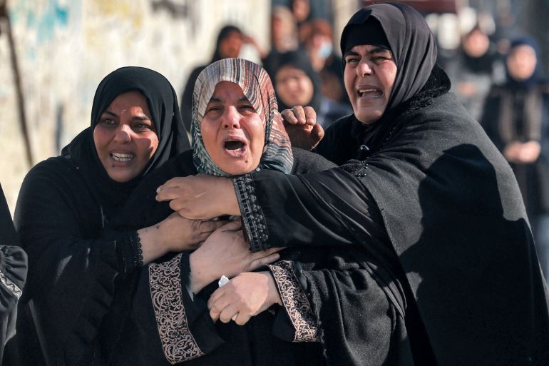 EDITORS NOTE: Graphic content / Women tend to the sister (C) of Palestinian journalist Adel Zorob, who was killed overnight during Israeli bombardment, as she mourns his death in Rafah in the southern Gaza Strip on December 19, 2023 amid continuing battles between Israel and the militant group Hamas. (Photo by MOHAMMED ABED / AFP)