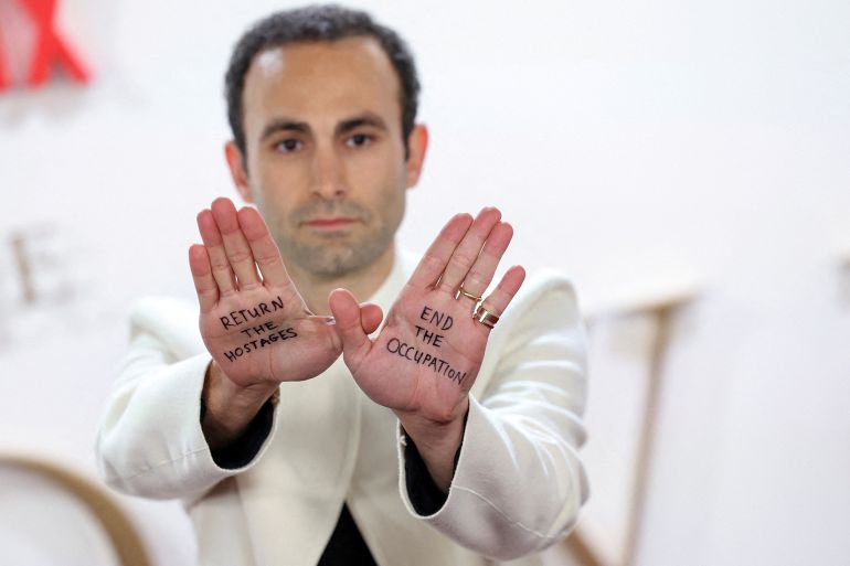 Cast member Khalid Abdalla shows slogans written on his hands regarding to the ongoing conflict between Israel and the Palestinian Islamist group Hamas, as he attends the premiere for the second part of Season 6 of the TV series "The Crown" in London, Britain, December 5, 2023. REUTERS/Isabel Infantes TPX IMAGES OF THE DAY
