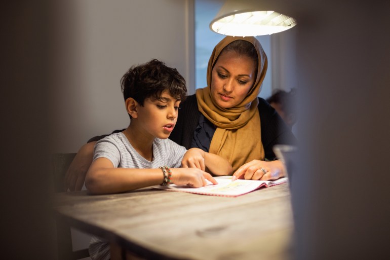 Mother and son reading book in darkroom at home