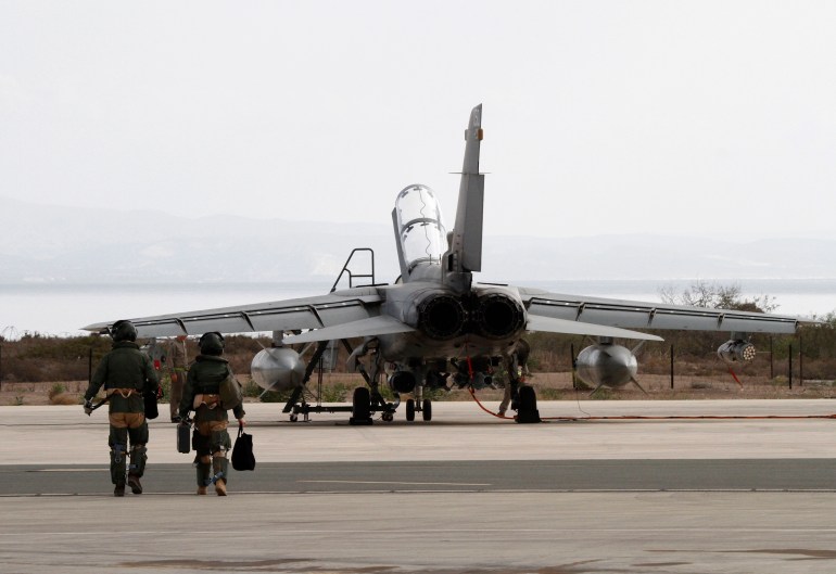 Servicemen walk near a British Tornado jet at the RAF Akrotiri in Cyprus September 27, 2014. Britain's parliament approved air strikes against Islamic State (IS) insurgents in Iraq by a decisive margin on Friday, paving the way for the Royal Air Force to join U.S.-led military action with immediate effect. Six Cyprus-based Tornado GR4 fighter-bombers were on standby to take part in initial sorties after Prime Minister David Cameron recalled parliament from recess to back military action following a formal request from the Iraqi government. REUTERS/Stringer (CYPRUS - Tags: POLITICS TRANSPORT CIVIL UNREST MILITARY)