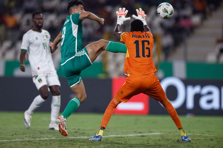 Mauritania's goalkeeper #16 Babacar Niasse makes a save as Algeria's forward #9 Baghdad Bounedjah makes an attempt at goal during the Africa Cup of Nations (CAN) 2024 group D football match between Mauritania and Algeria at Stade de la Paix in Bouake on January 23, 2024. (Photo by KENZO TRIBOUILLARD / AFP)