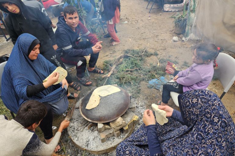 فلسطينيات نازحات يعددن ما يسمى شعبياً "خبز الصاج" في مخيم للنازحين غرب مدينة رفح أقصى جنوب قطاع غزة على الحدود مع مصر.