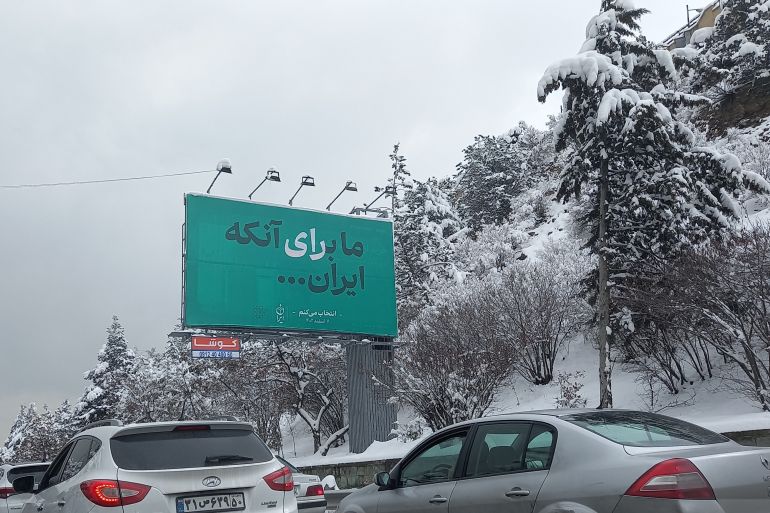 بلدية طهران تعلق لافتات في المدينة كتب عليها _نحن نشارك في الانتخابات كي تصبح إيران..._ (الجزيرة)