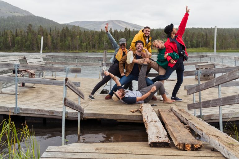 Finland, Lapland, portrait of happy playful friends posing on jetty at a lake