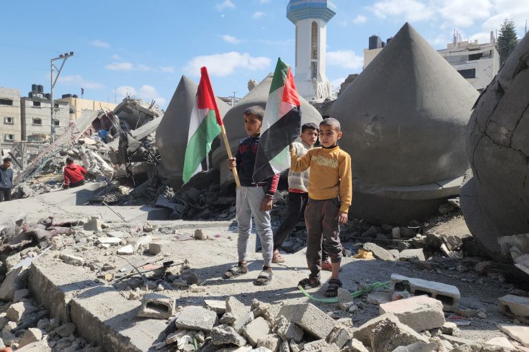 أطفال يلوحون بالعلم الفلسطيني فوق أنقاض مسجد الفاروق المدمر بمخيم الشابورة بمدينة رفح-رائد موسى-رفح-الجزيرة نت