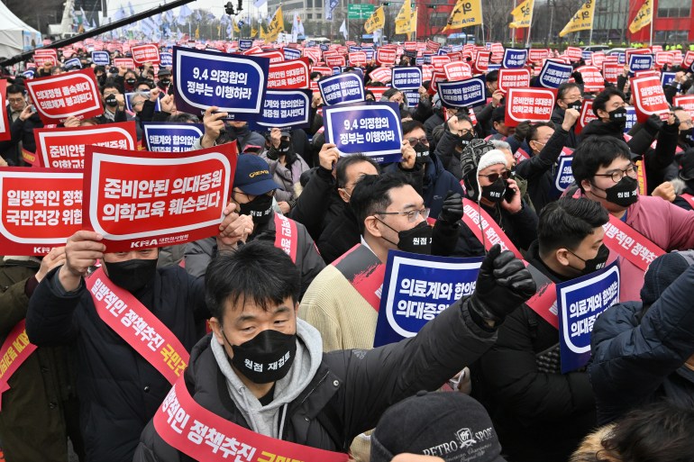 (FILES) Doctors hold up placards reading "Opposition to the increase in medical schools" during a rally against the government's plan to raise the annual enrolment quota at medical schools, in Seoul on March 3, 2024. - South Korea said on March 11, 2024 it had started procedures to suspend the medical licences of 4,900 junior doctors who have resigned and stopped working to protest against government medical training reforms. (Photo by Jung Yeon-je / AFP)