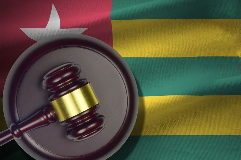 Togo flag with judge mallet and handcuffs in dark room. Concept of criminal and punishment, background ...