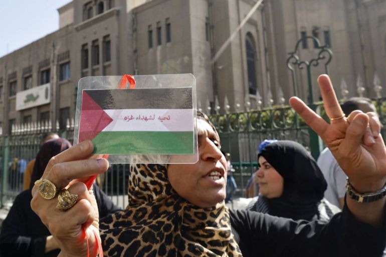 A woman holds a card with the image of the Palestinian flag and the the words that read, 'We Salute the martyrs of Gaza' during a protest supporting the Palestinian people following Friday Noon prayers outside the al-Azhar Mosque in Cairo on October 20, 2023, amid the ongoing battles between Israel and the Palestinian group Hamas. (Photo by Khaled DESOUKI / AFP)