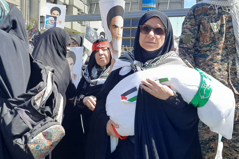 إيرانية تحتضن نعشا صغيرا للتنديد بالمجازر الإسرائيلية بحق أطفال غزة (الجزيرة)