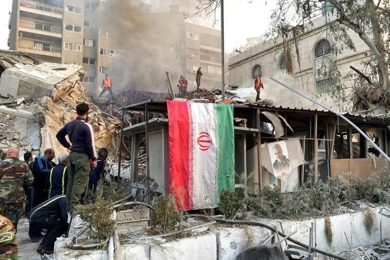An Iranian flag hangs as smoke rises after what the Iranian media said was an Israeli strike on a building close to the Iranian embassy in Damascus, Syria April 1, 2024. REUTERS/Firas Makdesi
