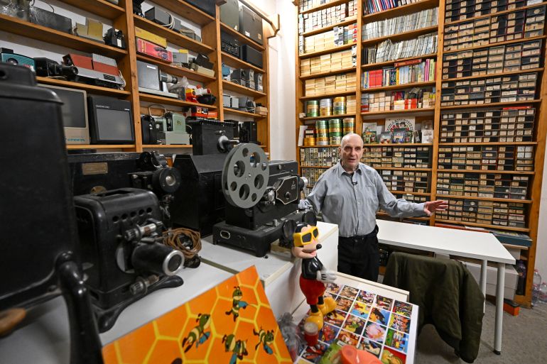 Ferenc Biro, filmstrip collector and owner of the Virtual Museum of Slide Film shows their museum objects in Budapest on February 18, 2024, as the Hungarian 'Diafilmgyarto' celebrates its 70th anniversary with various events including monthly screenings of slide films at a Budapest cinema attracting dozens of children and nostalgic adults. - A century-old storytelling medium, its Hungarian producer has seen a resurgence in demand for filmstrips since the 2000s as enthusiasts appreciate the chance for slower, more intimate storytelling in the age of increasingly fast-paced entertainment. Filmstrips -- sometimes called slide films -- are printed on rolls of film, but unlike traditional movies, images can be shown for any amount of time, and are not meant to create the illusion of motion. (Photo by ATTILA KISBENEDEK / AFP) / TO GO WITH AFP STORY BY ANDRAS ROSTOVANYI - TO GO WITH AFP STORY by Andras ROSTOVANYI