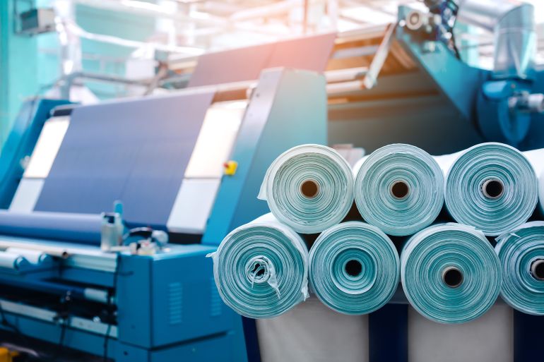 Rolls of industrial cotton fabric for clothing cloth textile manufacture on machine.