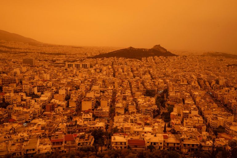 This photograph taken on April 23, 2024, in Athens shows a view of the city of Athens shrouded in haze, as southerly winds carried waves of dust to the city. - Clouds of dust blown in from the Sahara covered Athens and other Greek cities on April 23, 2024, one of the worst such episodes to hit the country since 2018, officials said. The yellow-orange haze smothered several regions, limiting visibility and prompting warnings of breathing risks from the authorities. (Photo by Angelos TZORTZINIS / AFP)