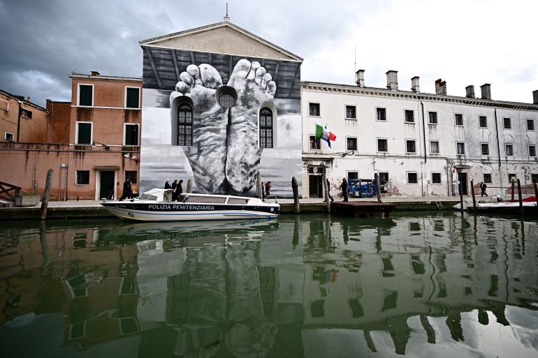 A mural by artist Maurizio Cattelan is seen outside Giudecca Womens Prison hosting the Holy See pavilion during the pre-opening of the 60th Venice Biennale art show, on April 18, 2024 in Venice. - (Photo by GABRIEL BOUYS / AFP) / RESTRICTED TO EDITORIAL USE - MANDATORY MENTION OF THE ARTIST UPON PUBLICATION - TO ILLUSTRATE THE EVENT AS SPECIFIED IN THE CAPTION